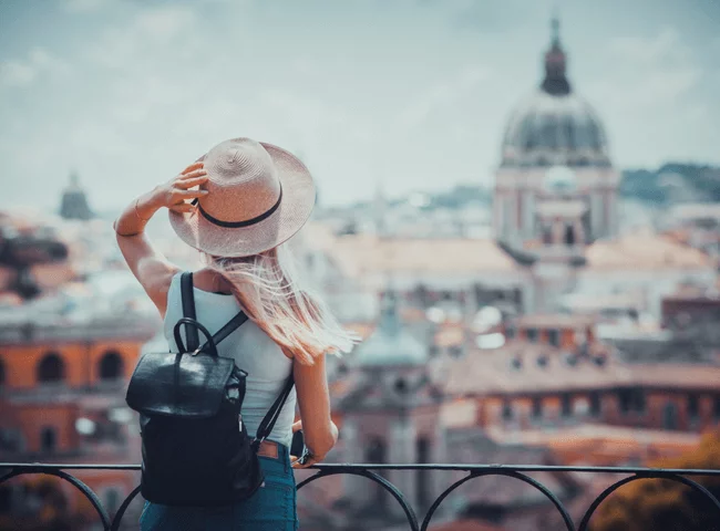 Young girl with camera in hand standing on the hill looking on the cathedral Vatican 1.png