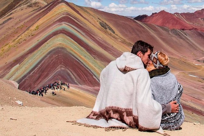 a man and woman kissing on a rainbow mountain