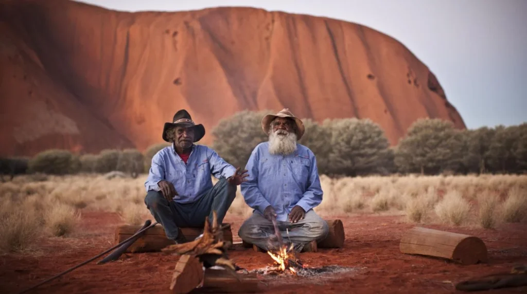 two men sitting next to a fire having best example of ecotourism