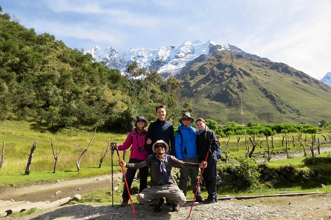 a group of people posing for a photo with a mountain in the background on Humantay Lake